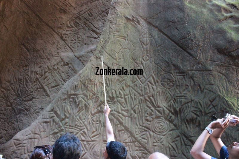 Guides explaining about edakkal caves to tourists 942